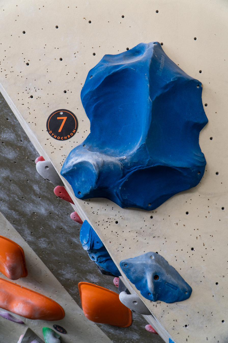 Setline-Routentag mit der Nummer 7 neben einem blauen Volumen an der Boulderwand