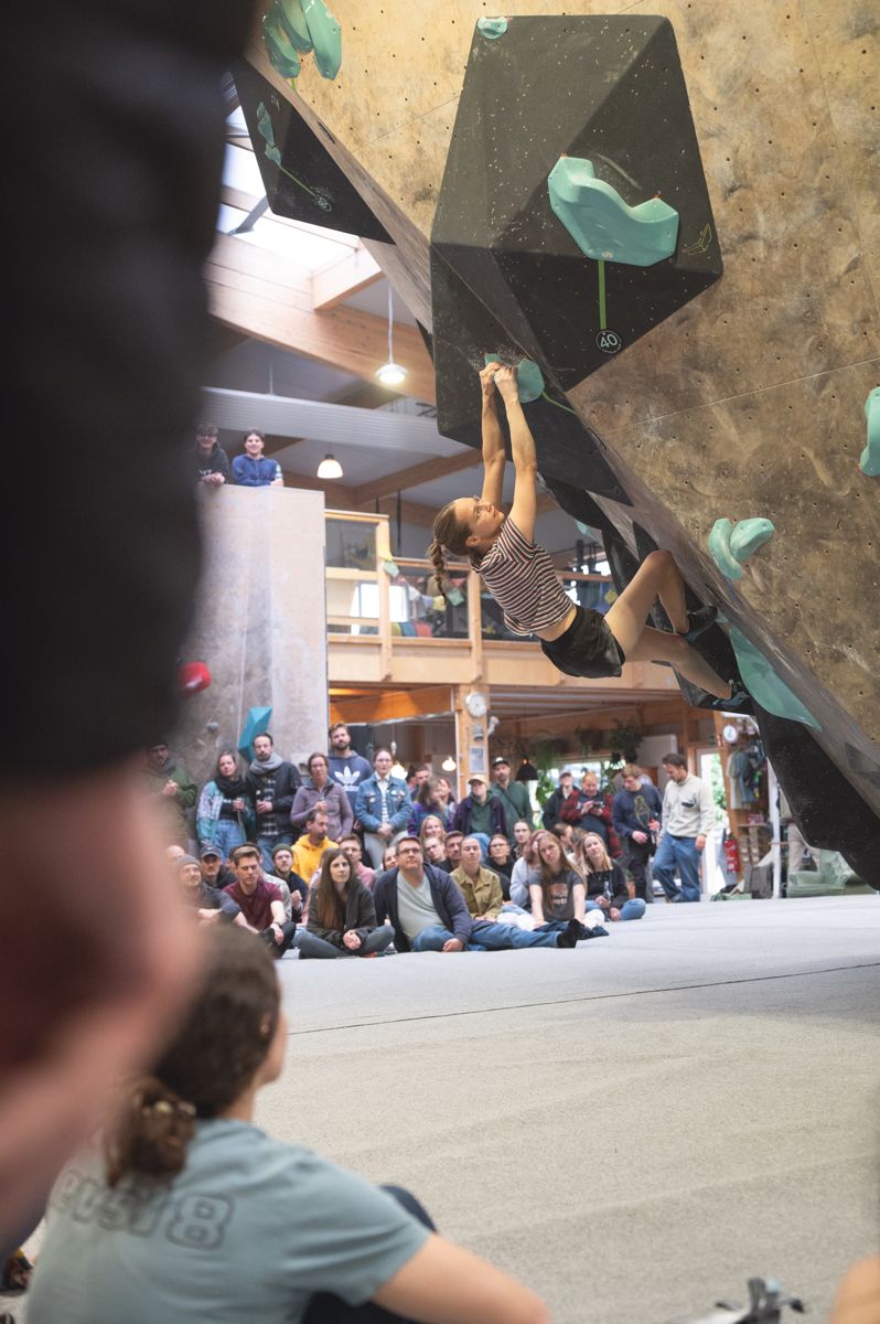 Kletterin an einem schwarzen Volume mit Cup-Schild 40, davor sitzendes Publikum