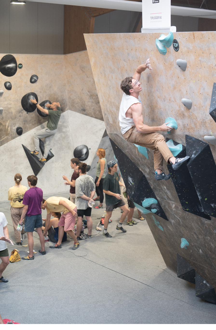 Boulderwettkampf in einer Halle mit Setline-Schildern an der Wand